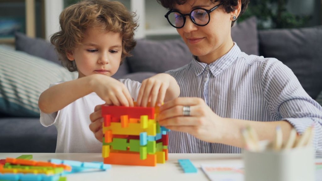 a woman and a child playing with a building set